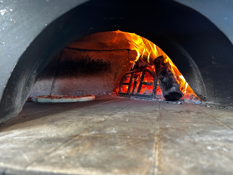 Interior del horno con fuego y pizza