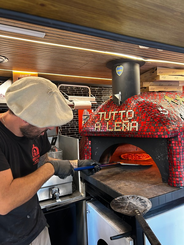 Chef colocando pizza en horno de leña